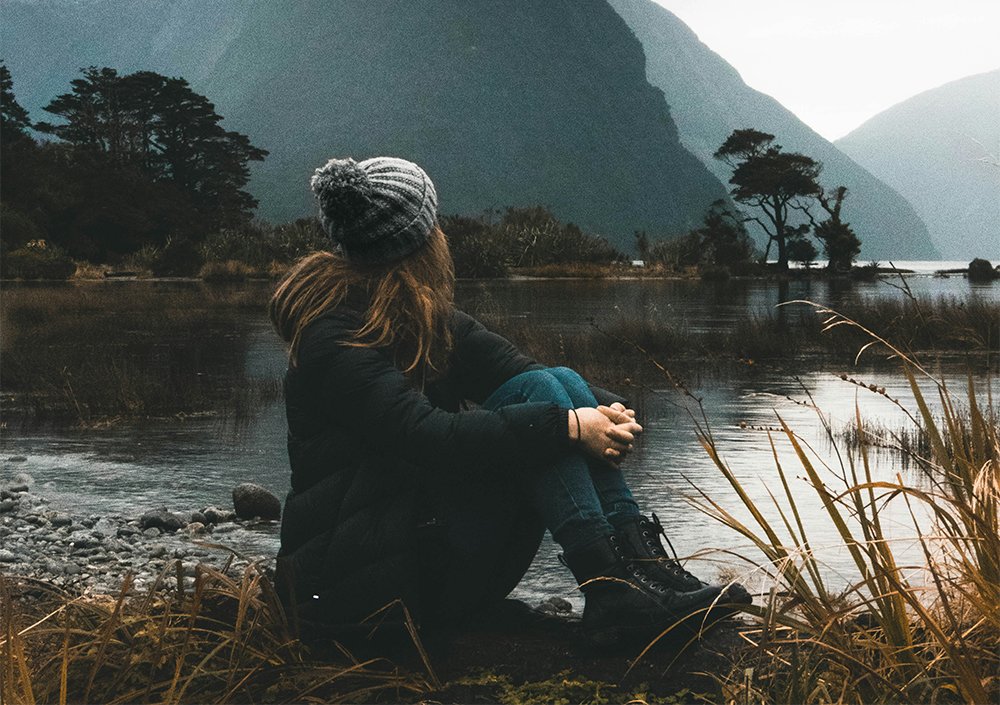 woman sitting by lake