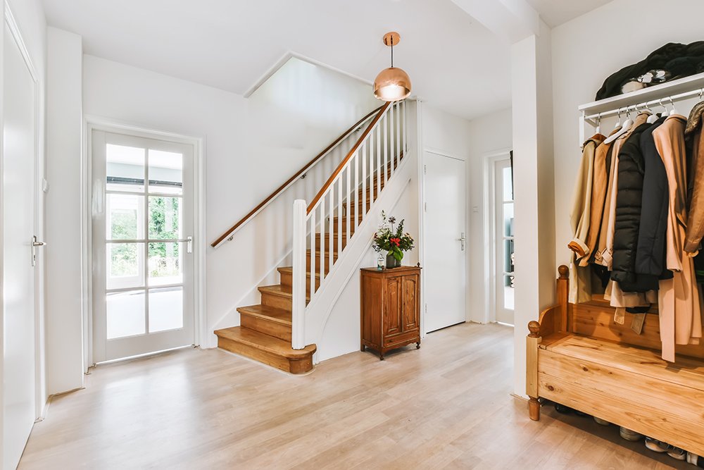 The interior of a beautiful hall with a clothes rack and a wooden staircase